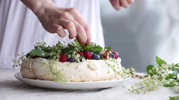 woman hands decorate a meringue cake on the table