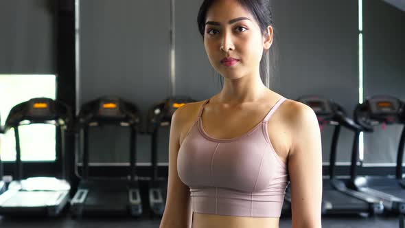 Smiling Asian Female Athlete Looking at Camera While Putting Arms Crossed Standing at Fitness Center