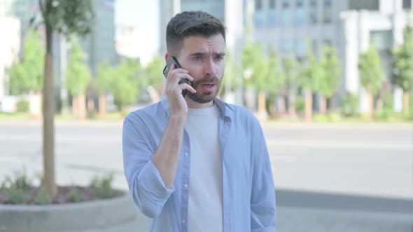 Angry Young Man Talking on Phone While Standing Outdoor