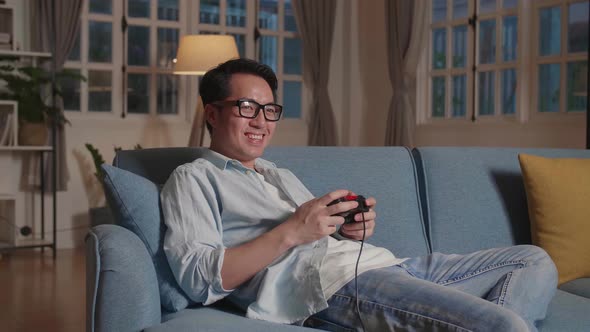 Asian Male Gamer Smiling While Playing A Game At Home