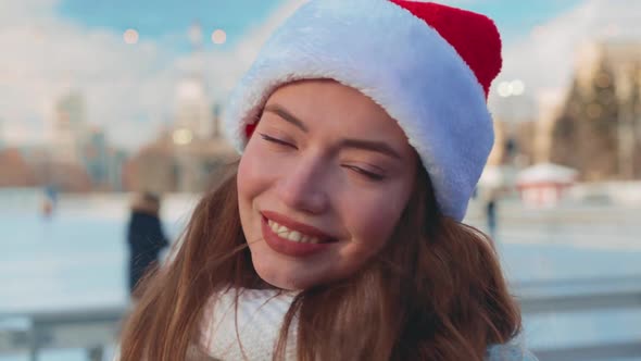 Young Smiling Woman Santa Hat Ice Skating Outside on Ice Rink Dressed White Sweater