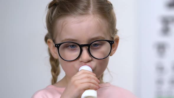 Adorable Caucasian Girl in Eyeglasses Drinking Milk Bottle, Vitaminized Beverage