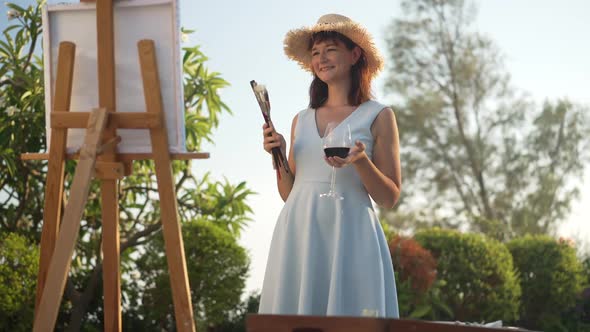 Carefree Elegant Female Artist Dancing in Slow Motion with Painting Tools and Red Wine in Hands