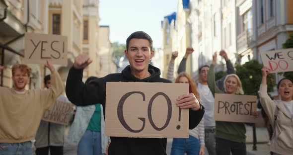 Man Activist Shows Go Poster with Multiraciaal People Protest Activists in Background