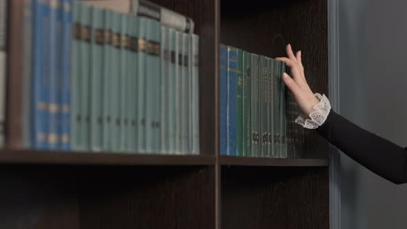 Hand of Female Taking Book From Bookshelf