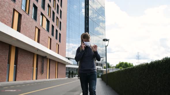 Man with Guitar in the Back and with a Medical Mask on Face Is Talking at the Phone