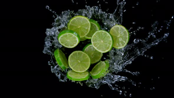 Super Slow Motion Shot of Rotating Exploded Lime Slices with Splashing Water on Black at 1000Fps