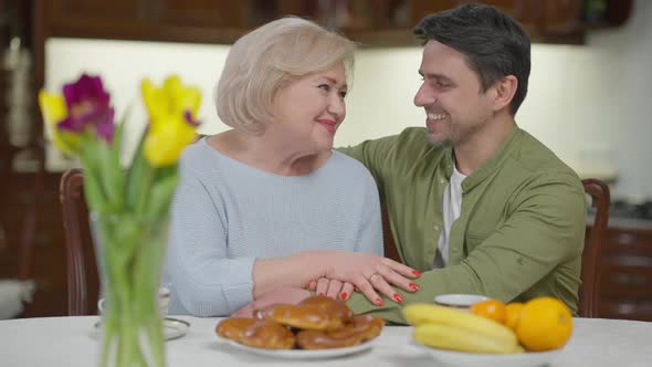 Portrait of Smiling Happy Relaxed Adult Son and Senior Mother Talking Turning Looking at Camera