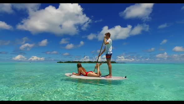 Man and lady sunbathe on luxury shore beach trip by clear lagoon with white sandy background of the 