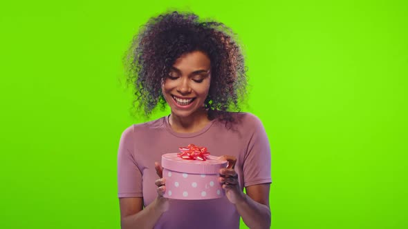 Young Dark Skinned Woman Happily Opening a Box with a Gift and Disappointed