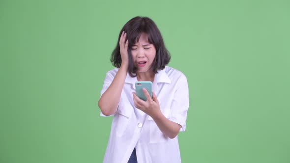 Stressed Asian Businesswoman Using Phone and Getting Bad News