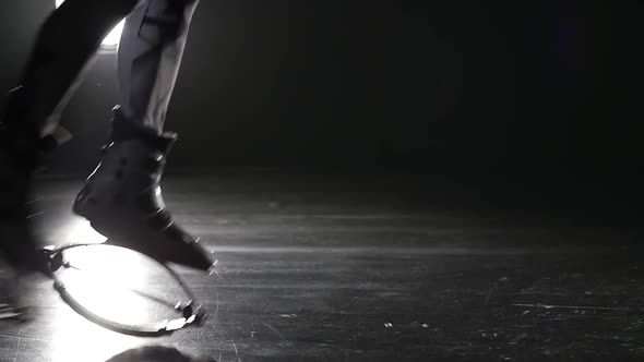 Close-up Slow Motion of Legs Jumping in Kangoo Shoes Against Spotlight