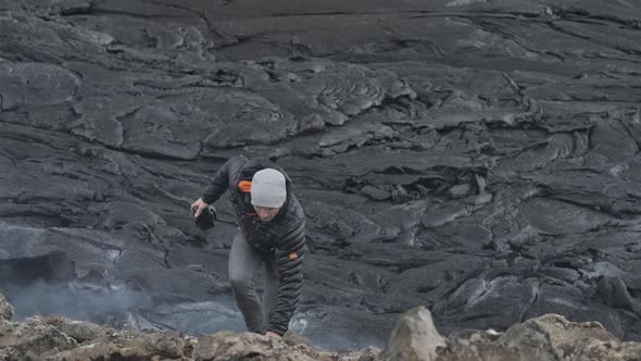 Photographer Walking Over Rocks Amongst Smoking Lava Field