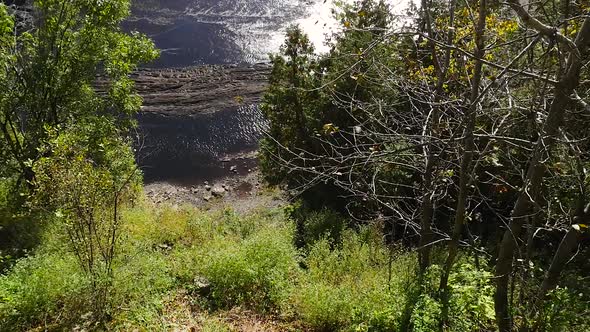 Looking Down A Very Steep Mountain Side Into Shallow Rocky Water