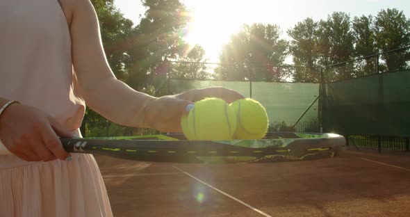 Close Up Female Hands Holding Tennis Balls on Racket Outdoors on Sunny Clay Court Background