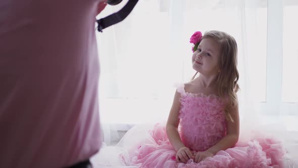 Beautiful Portrait Blonde of a Girl Child in a Pink Dress and with Rose Flower in Her Head