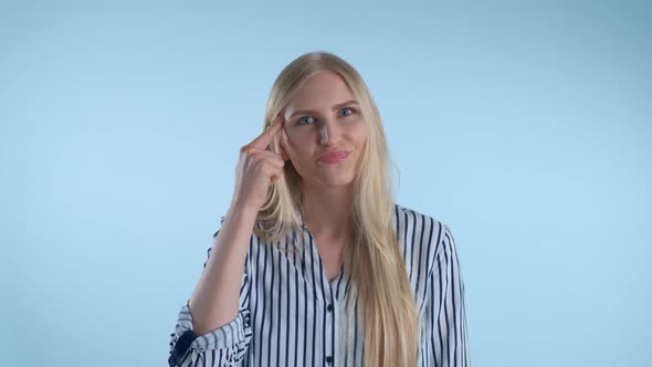 Attractive Woman Twisting Her Index Finger at Temple on Blue Background