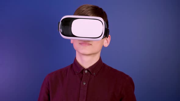 A Boy in a Virtual Reality Helmet Looks Around