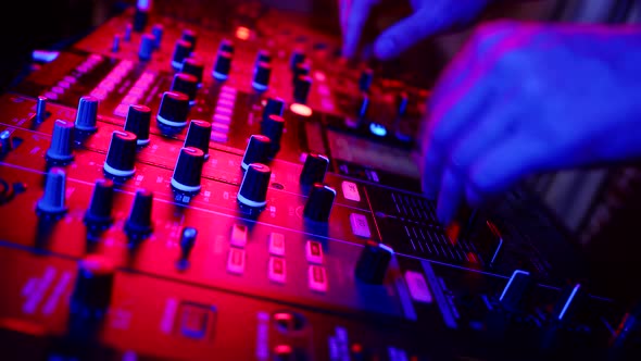 Professional Confident DJ is Adjusting Fader on Digital Music Console in Neon Light in Nightclub