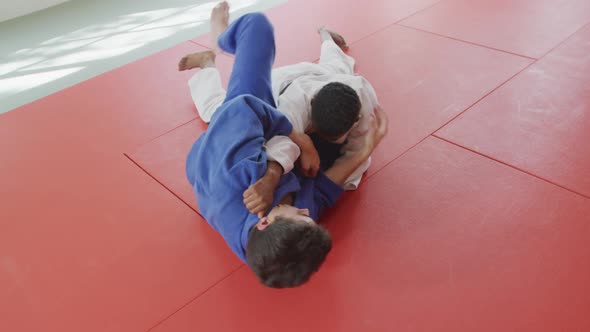 Mixed race male judo coach and teenage mixed race male judoka practicing judo