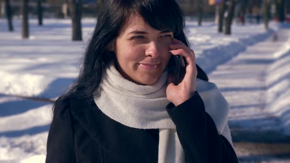 Happy Smiling Beautiful Girl Calls Number And Talks On Smart Phone. Sunny Day In Snow City Park 2