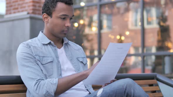 African Man Reading Documents while Sitting Outdoor