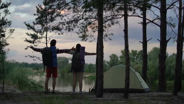 Happy Campers Raising Hands in Forerst, Enjoying River Landscape, Back View