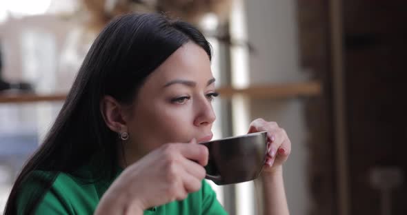 Woman Drinks Coffee Sitting in Cafe