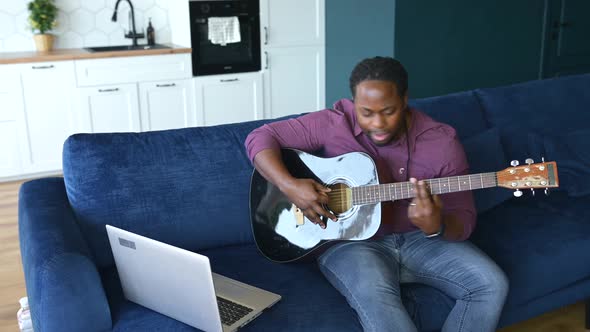 Concentrated AfricanAmerican Man Learning How to Play Guita
