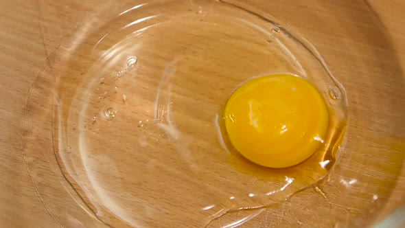 Breaking Egg for Cooking in Deep Glass Dish, Slow Motion