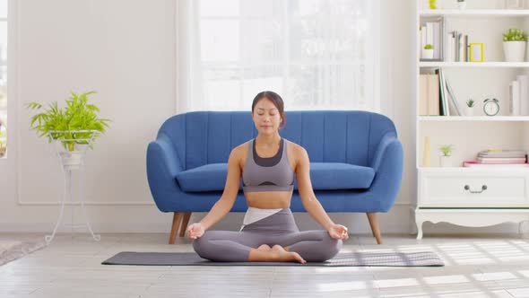 Calm of wellness Asian young woman sit on carpet breathing with yoga lotus pose