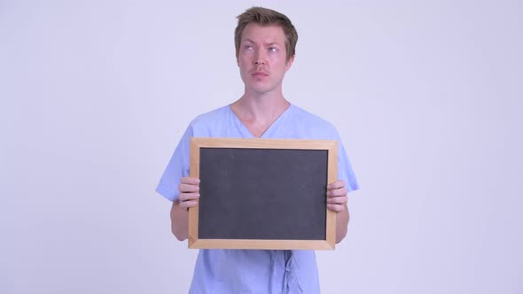 Happy Young Man Patient Thinking While Holding Blackboard