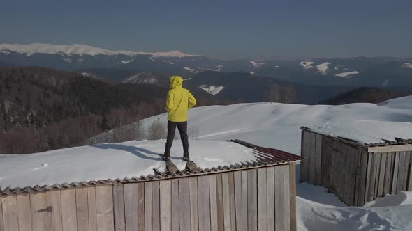 The Traveler Watches the Mountain Landscape Standing on the Roof of a Building in the Mountains