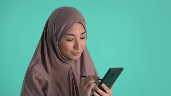 Thoughtful Asian Girl in Hijab Working on Phone