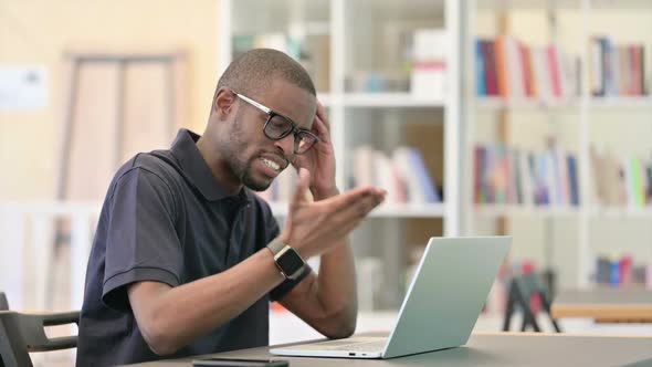 African Man Reacting to Loss on Laptop in Library