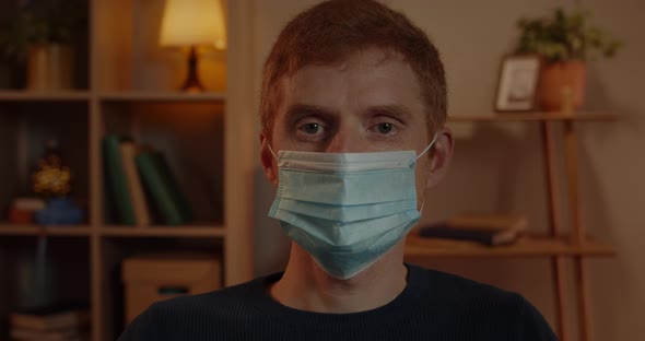 Portrait of Young Red Haired Man in Medical Protective Mask Turning Head and Looking To Camera