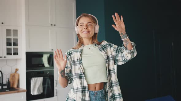 Young Blonde Lady Relaxing at Home Listening to Music in Wireless Headphones and Dancing Enjoying