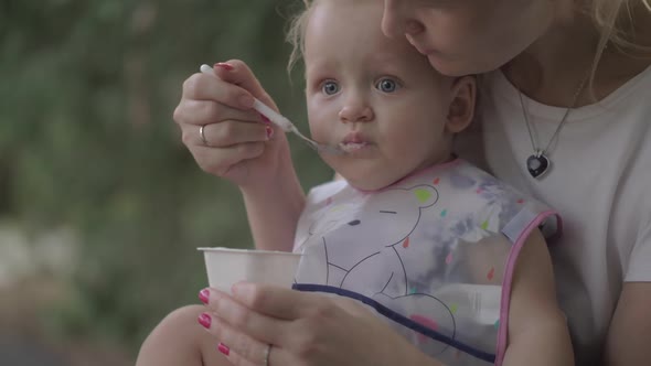 Mother Feeding Little Daughter Outside