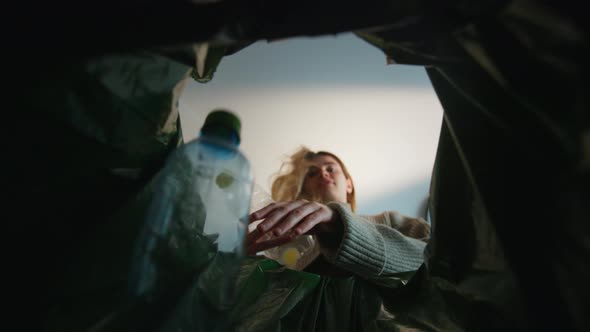 Woman Putting Empty Plastic Bottle in Recycling Bin in the Kitchen