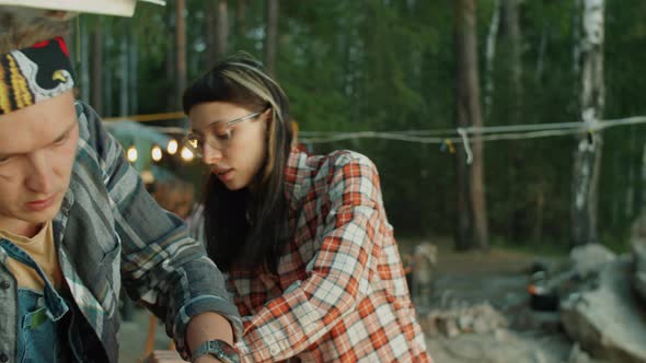 Young Tourists Setting Up Tent while Camping with Friends