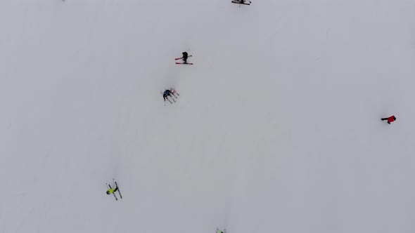 Aerial Top View of Skiers Go Down the Ski Slope on Ski Resort in Mountains
