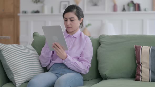 Indian Woman using Tablet While Sitting on Sofa