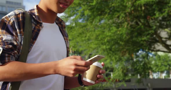 A man texting on his smartphone and holding coffee