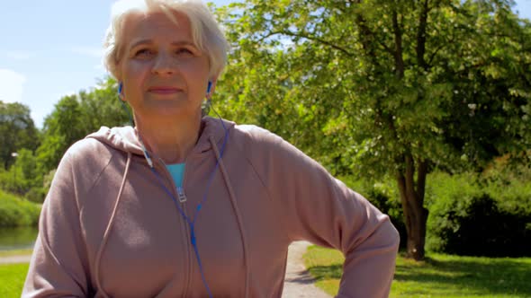 Senior Woman with Earphones Running in Summer Park