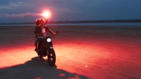 Couple Riding on Vintage Motorcycle with Red Burning Signal Fire After Sunset on Beach Slow Motion