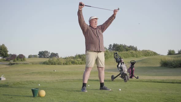 Senior Man Warming Up Before the Game, Holding a Golf Club Over His Head