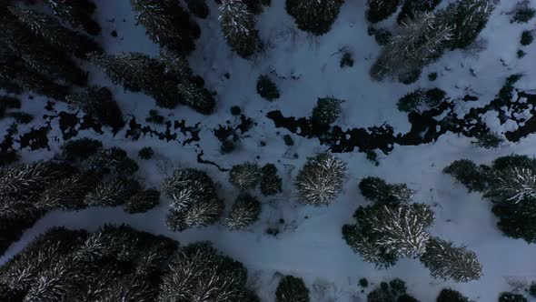 Top down aerial of nearly frozen river in forest - drone slowly ascending