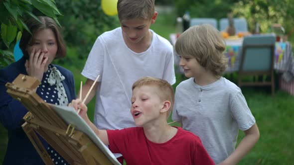 Group of Children Drawing on Easel Talking in Slow Motion Smiling Standing on Backyard Outdoors