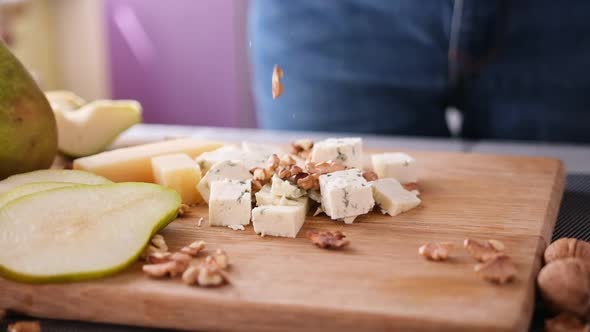 Making Pear and Blue Cheese Salad  Walnuts Falling on a Wooden Cutting Board