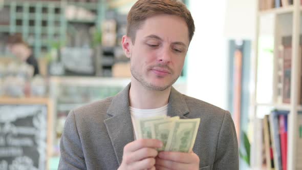 Portrait of Successful Young Man Counting Dollars